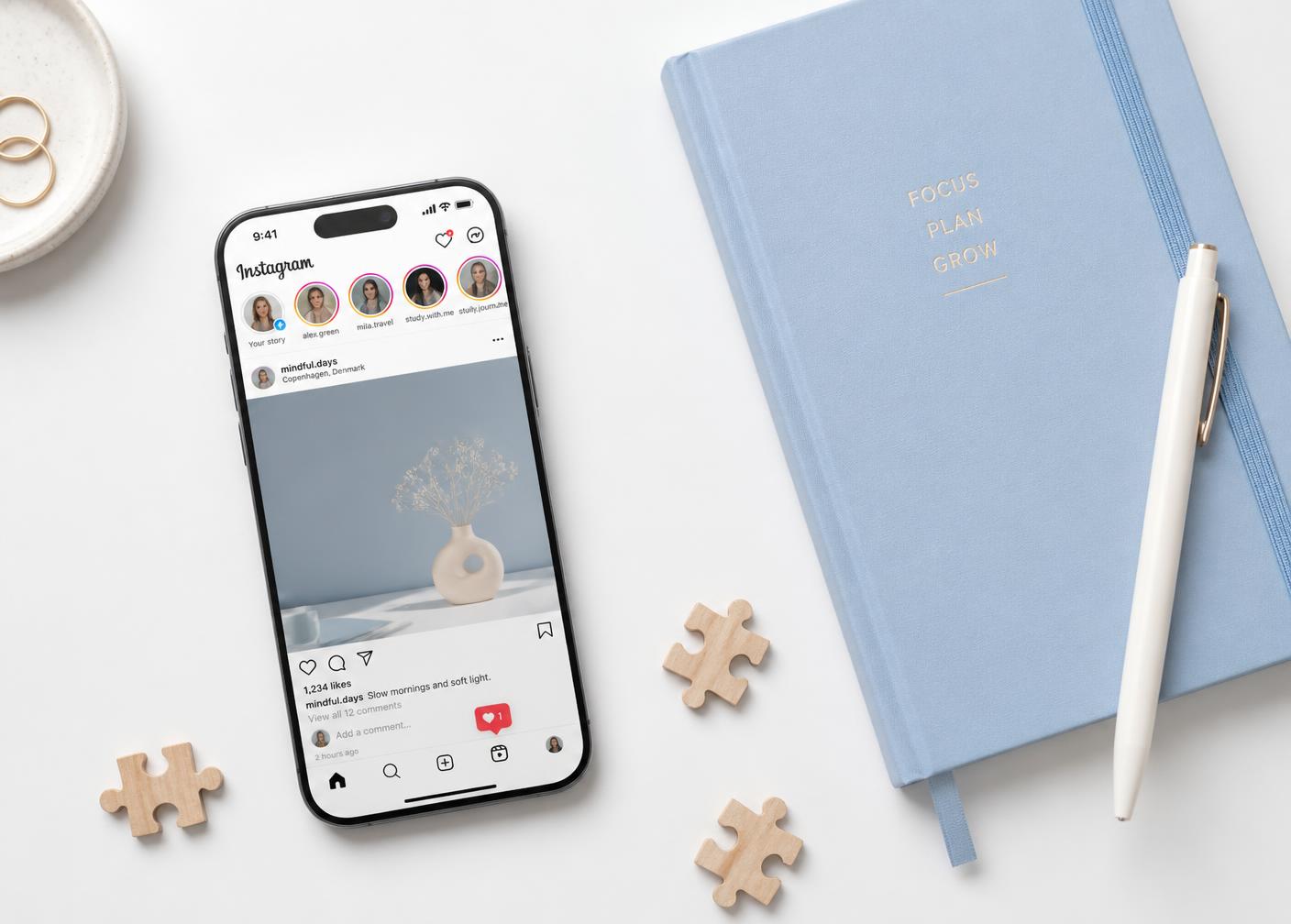 Phone showing a social media feed beside a light blue notebook and wooden puzzle pieces